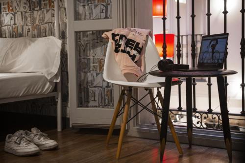 a bedroom with a bed and a desk with a laptop on a chair at room00 Chueca Hostel in Madrid