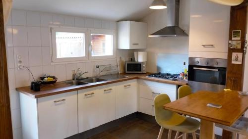 une cuisine avec des armoires blanches et une table en bois dans l'établissement Maison 3 chambres, à Azur