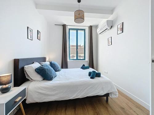 ein Schlafzimmer mit einem Bett mit blauen Kissen und einem Fenster in der Unterkunft L'Alcazar - Appartement à deux pas des halles - Climatisation in Narbonne