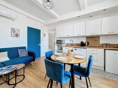 une cuisine et une salle à manger avec une table et des chaises bleues dans l'établissement L'Alcazar - Appartement à deux pas des halles - Climatisation, à Narbonne