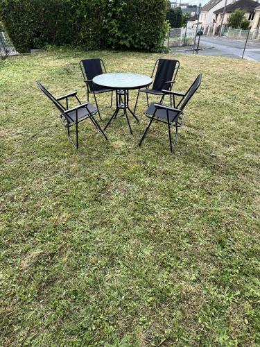 three chairs and a table in the grass at La maison des amis in Beauvais