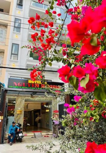 a man standing in front of a building with red flowers at Nguyên Hương Hotel in Ho Chi Minh City