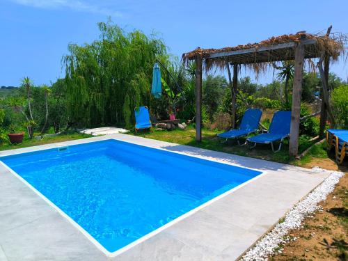 a swimming pool with blue chairs and an umbrella at Olive and Blue Retreat in Halikounas