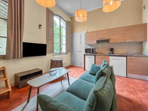un salon avec un canapé bleu et une cuisine dans l'établissement Cosy Appartement vue sur le Palais des Papes depuis la loggia, à Avignon