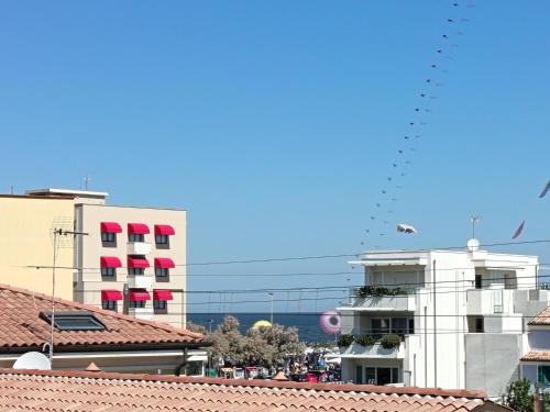 a group of birds flying in the sky over buildings at La casetta rosa in Fano