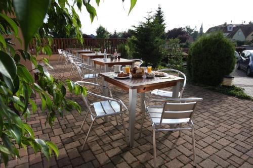 a row of tables and chairs on a brick patio at Hôtel Restaurant Les Alizés in Lipsheim