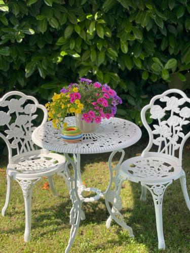 a table with a vase of flowers sitting between two chairs at Ca del Gno in Luni