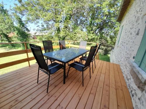 une table et des chaises sur une terrasse en bois dans l'établissement Gite de France Lacam, à Bannes