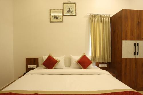 a bedroom with a bed with red and white pillows at hotel pride & restaurant in Dabok
