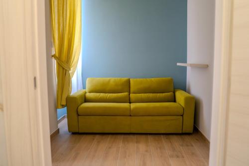 a yellow couch in a room with a window at Luxury Acclavio Apartments in Taranto