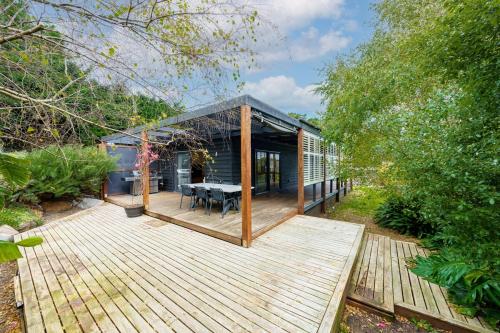 a house with a wooden deck with a table at Acacia Rise - The Ultimate Peninsula Getaway in Cape Schanck