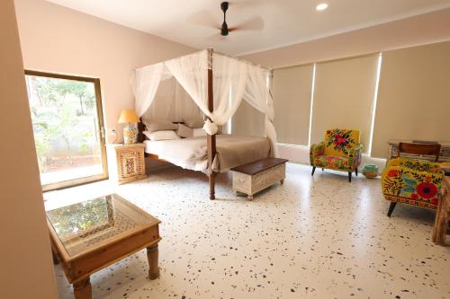 a bedroom with a canopy bed and a chair at Vanaswara in Kolād