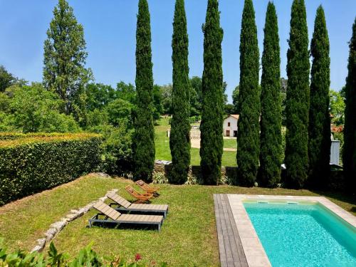 un jardin avec une piscine et un groupe d'arbres dans l'établissement Maison La Fleur Godard - Clos Fontaine, à Saint-Cibard