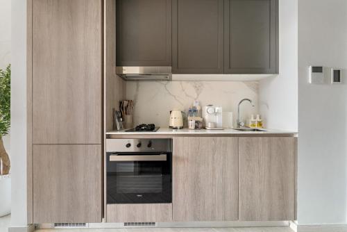 a kitchen with a stove and a sink and cabinets at FIRST CLASS Studio Luxe & Cozy Vibes in Dubai
