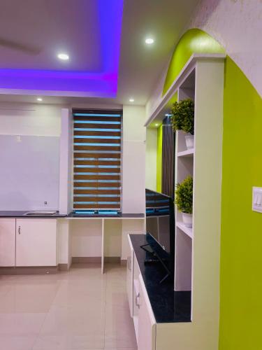 a kitchen with white cabinets and a green wall at Studio suites in Trivandrum