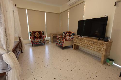 a living room with two chairs and a flat screen tv at Vanaswara in Kolād