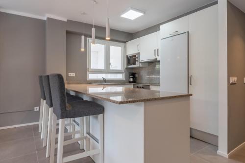 cocina con armarios blancos y barra con taburetes en Ponent Cala Ratjada Apartments A, en Cala Ratjada
