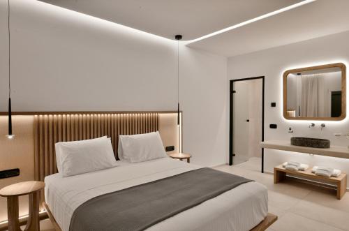 a bedroom with a large bed and a mirror at Etere Luxury Suites in Agios Ioannis Mykonos
