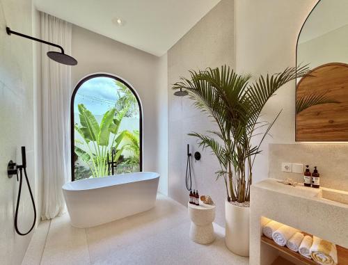 a bathroom with a tub and a large window at Dolce x The Young Villas in Uluwatu