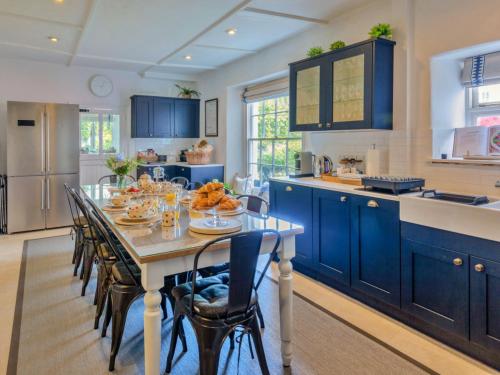 een keuken met blauwe kasten en een tafel en stoelen bij Finest Retreats - Blue Monkey in Cawsand