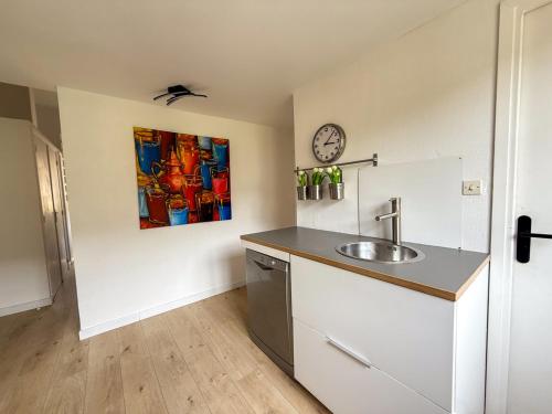 une cuisine avec un évier et une horloge murale dans l'établissement Appartement pour 6 personnes , plage de Saint Clair, au Lavandou