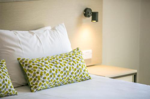 a bed with yellow and white pillows on it at Nightcap at Blue Cattle Dog Hotel in St Marys