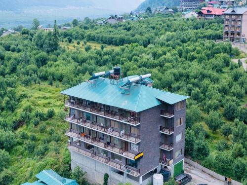 an apartment building with a blue roof on a hill at Himalayan Spurge Villa in Manāli