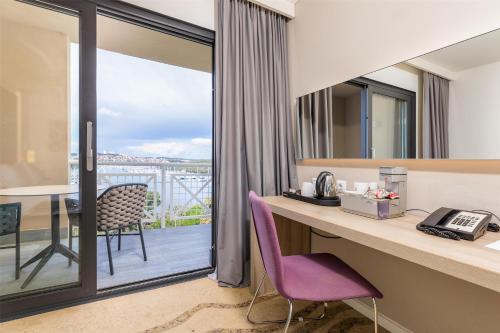a room with a desk with a phone and a balcony at Park Plaza Histria Pula in Pula