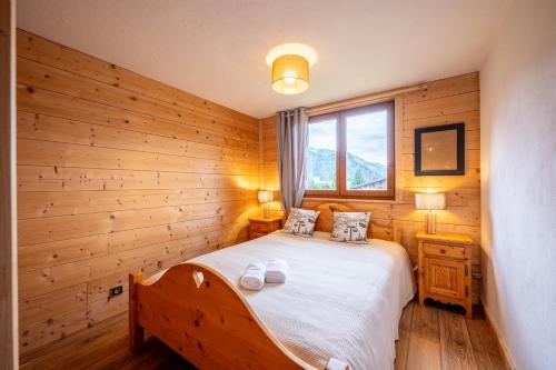 une chambre avec un lit avec des murs en bois et une fenêtre dans l'établissement Le Refuge de Rochebrune - vue montagne, à Megève