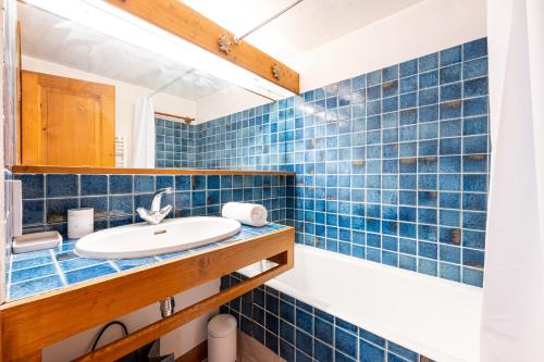 une salle de bain carrelée bleue avec un lavabo et une baignoire dans l'établissement Le Refuge de Rochebrune - vue montagne, à Megève