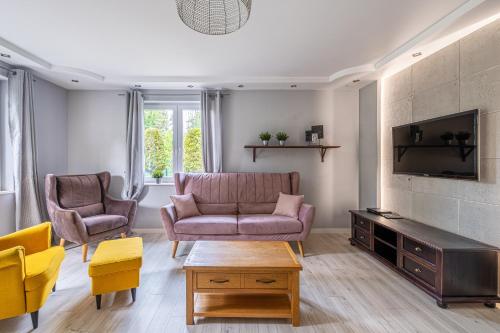 een woonkamer met een bank en twee stoelen bij Sunny Sobieszewo in Gdańsk