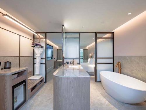 Un baño con una gran bañera blanca y un lavabo. en Mercure Shanghai Lujiazui, en Shanghái