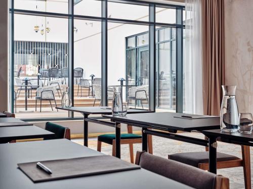 a restaurant with tables and chairs and a large window at Mövenpick Grand Hotel Wroclaw in Wrocław