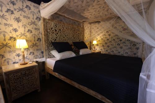 a bedroom with a bed and two lamps and wallpaper at Vanaswara in Kolād
