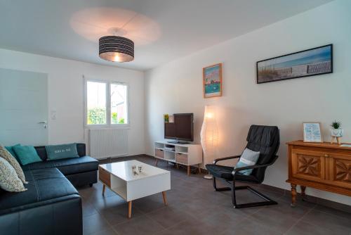 a living room with a couch and a chair and a tv at La Bulle de Landrezac - Jacuzzi et Proche Plage in Sarzeau