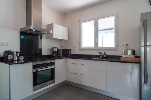 a kitchen with white cabinets and black counter tops at La Bulle de Landrezac - Jacuzzi et Proche Plage in Sarzeau