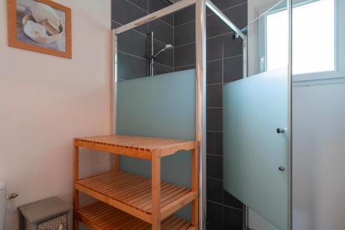 a shower stall with a wooden shelf in a bathroom at La Bulle de Landrezac - Jacuzzi et Proche Plage in Sarzeau