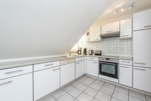 a white kitchen with white cabinets and appliances at Wenkendorf 52 MeErholung in Wenkendorf auf Fehmarn
