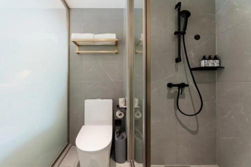 a bathroom with a shower with a toilet and a glass shower door at Atour Light Hotel Dalian Xinghai Square Hang Lung Shopping Center in Dalian