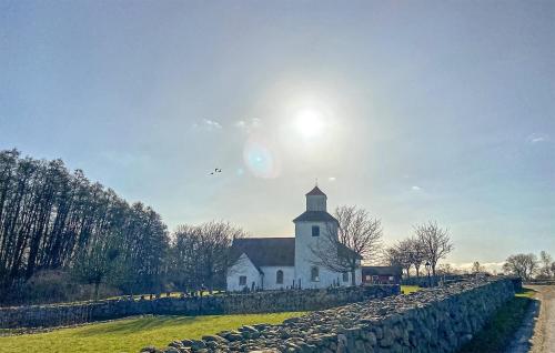a white church with the sun behind a stone wall at Beautiful Home In Fjälkinge in Fjälkinge
