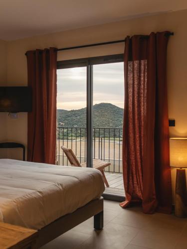 une chambre avec un lit et un balcon avec vue dans l'établissement Résidence Oradoro - Nouvel établissement, à Belgodère