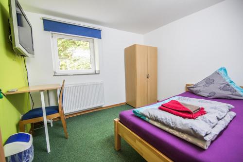 a bedroom with a bed and a desk and a television at Hotel Burghof in Stolberg