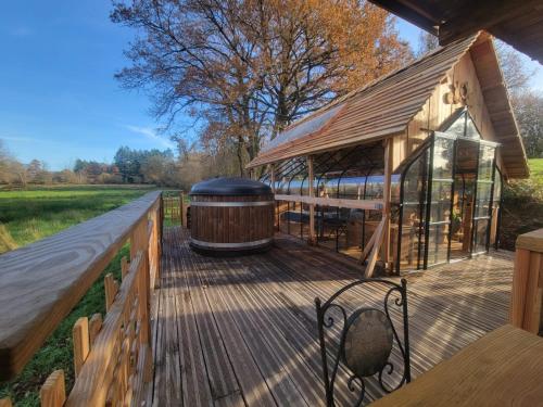 a large wooden deck with a hot tub on it at La terre du milieu 87 in Saint-Sulpice-les-Feuilles