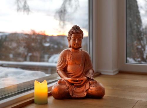 a statue sitting on the floor next to a candle at Berghotel Hoher Knochen - Ruhe & Natur in Winterberg