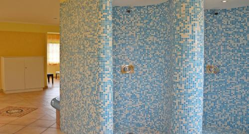 a bathroom with blue mosaic tiles on the wall at Hotel Fantur in Velden am Wörthersee
