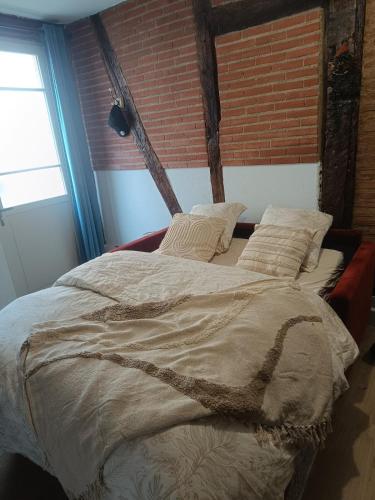 un grand lit dans une pièce avec un mur de briques dans l'établissement Studio typique Albigeois - quartier calme, à Lescure-dʼAlbigeois