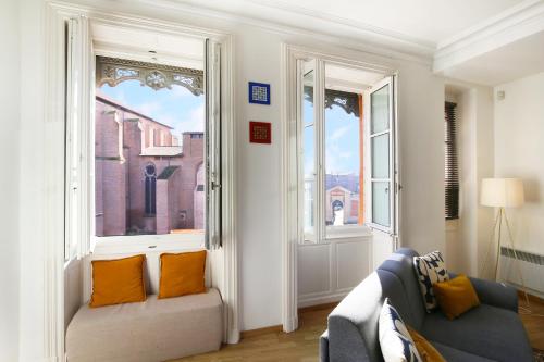 un salon avec un canapé et deux fenêtres dans l'établissement Metz by Yumē, à Toulouse
