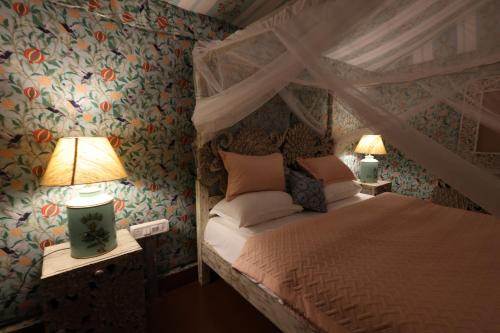 a bedroom with a canopy bed and two lamps at Vanaswara in Kolād