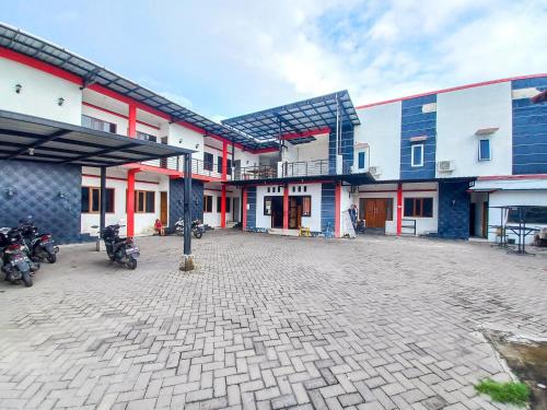 a group of buildings with motorcycles parked in a parking lot at RedDoorz Syariah at Homestay Bougenville near Taman Alun-Alun Kota Lamongan in Lamongan