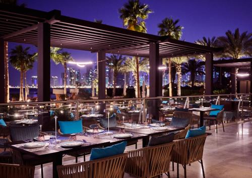 een restaurant met tafels en stoelen 's avonds bij InterContinental Doha Beach & Spa by IHG in Doha